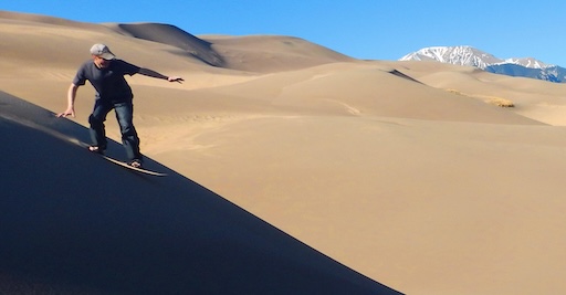 Visitors splashing in seasonal Medano Creek with dunes in background