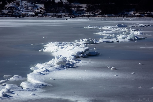 Frozen Lake Suwa in winter with distant shrine
